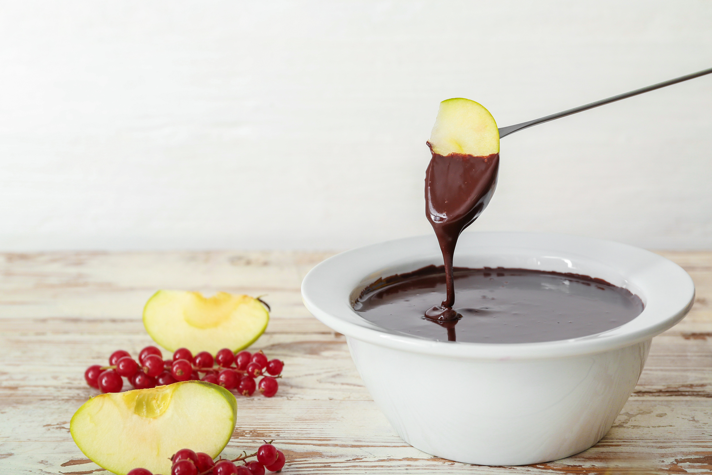 Dipping of Tasty Apple into Bowl with Chocolate Fondue
